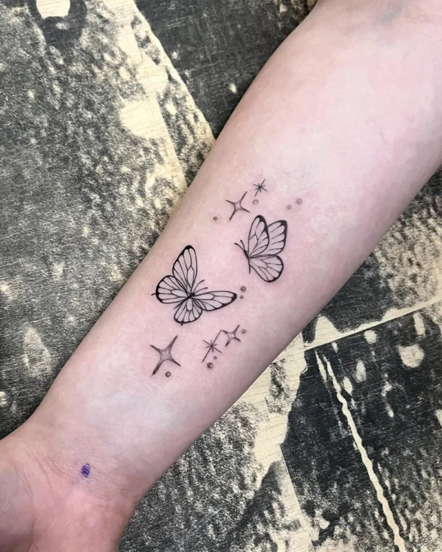 Mariposas tatuadas en fine line en el antebrazo